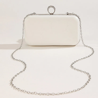 White clutch bag with a chain strap on a light beige background