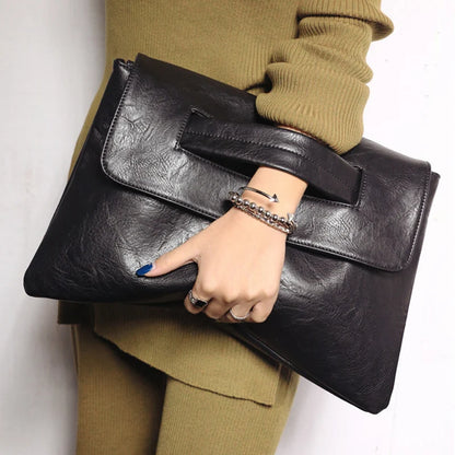 Person holding a black leather clutch bag against a white background