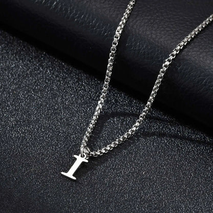 Silver necklace with a 'I' pendant on a black textured surface