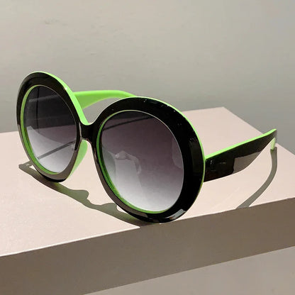 Sunglasses with green and black frame on a light surface