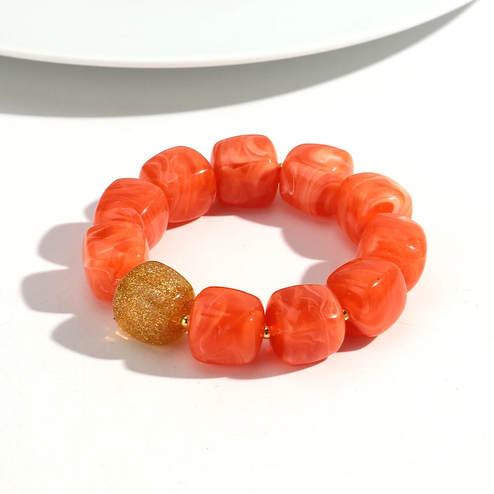 Orange marbled bracelet with a gold bead on a white background