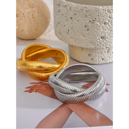 Gold and silver spiral bracelets on a neutral background