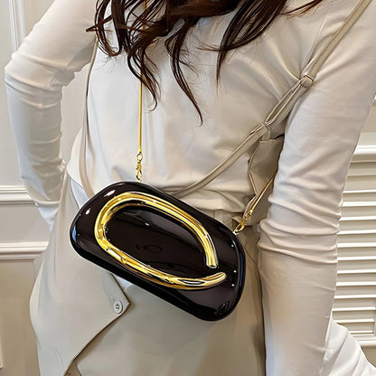 Person wearing a black and gold handbag with a neutral background