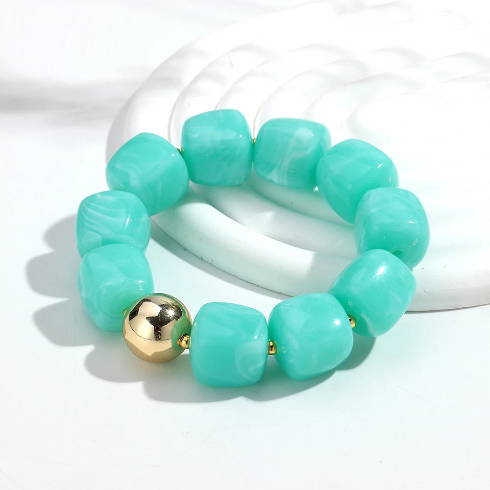 Turquoise beaded bracelet with a gold bead on a white background