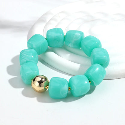 Turquoise beaded bracelet with a gold bead on a white background