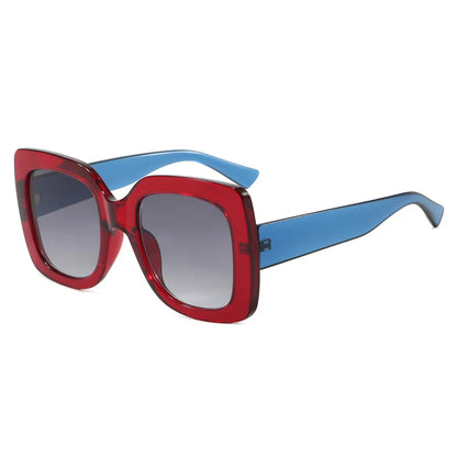 Oversized square sunglasses with a translucent red front frame, blue temples, and gradient grey lenses, shown on a plain white background.