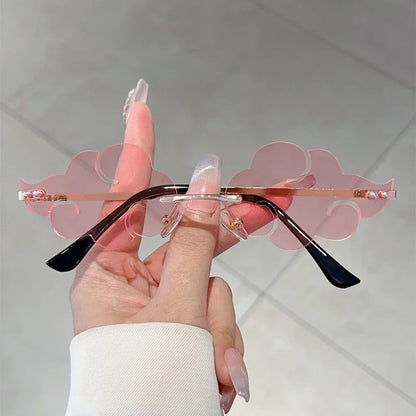 Hand holding a pair of sunglasses with pink and black design against a light background