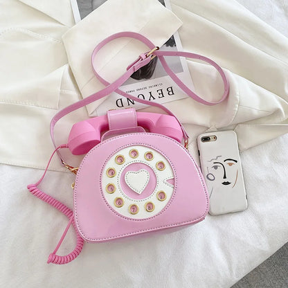 Pink phone-shaped handbag with a heart design on a white surface