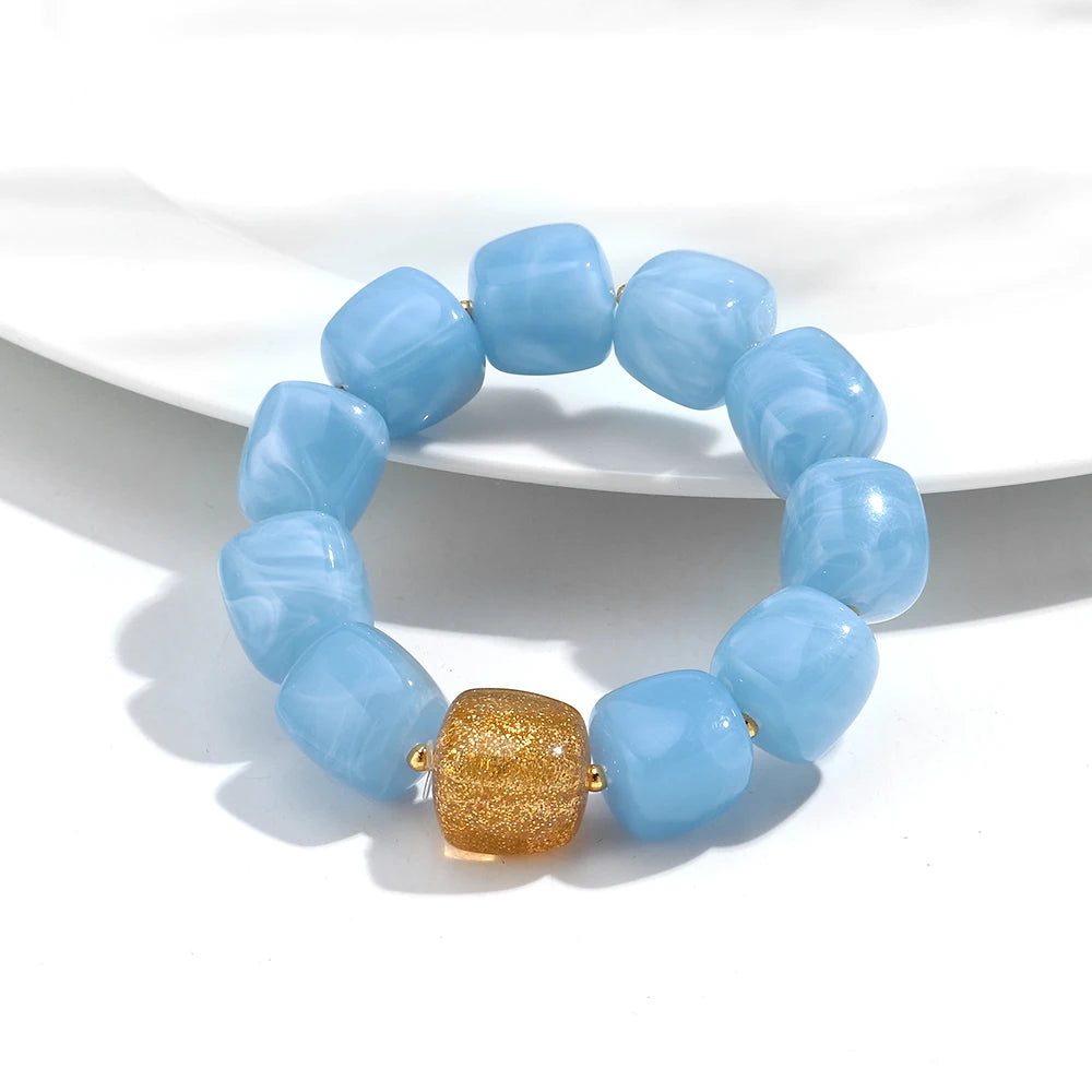 Blue beaded bracelet with a gold accent on a white background