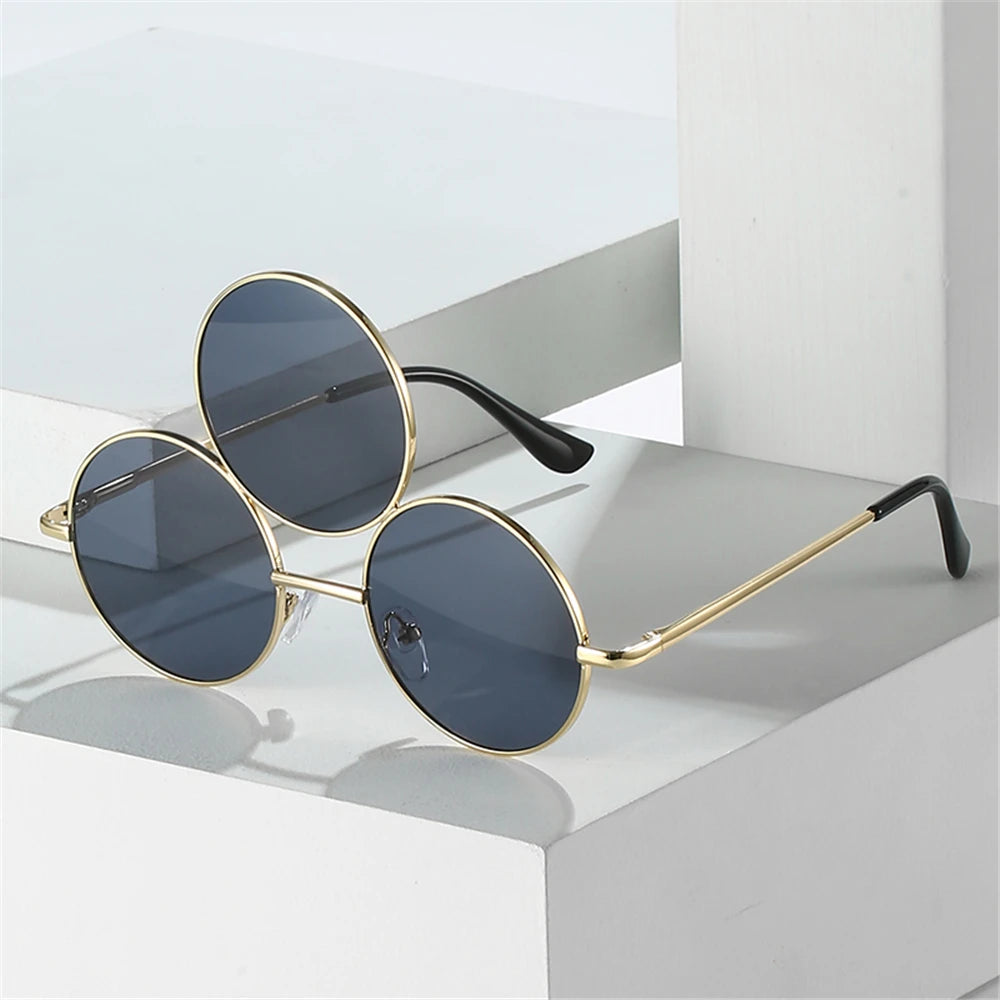 Round sunglasses with gold frames and dark lenses on a white surface