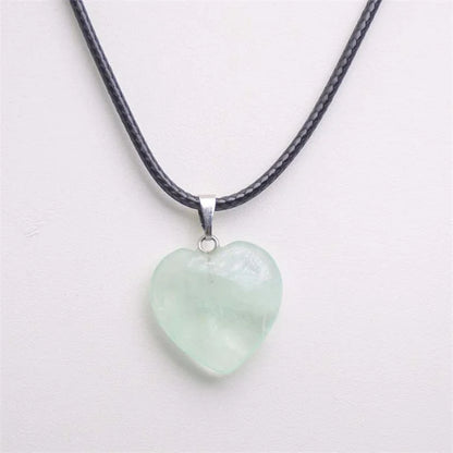 Heart-shaped jade pendant on a black cord against a white background