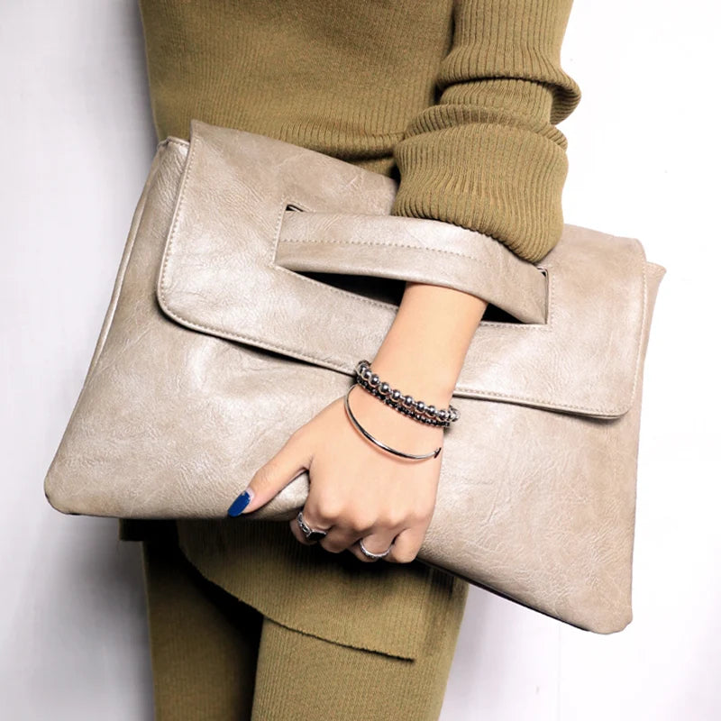 Person holding a beige clutch bag with a plain background