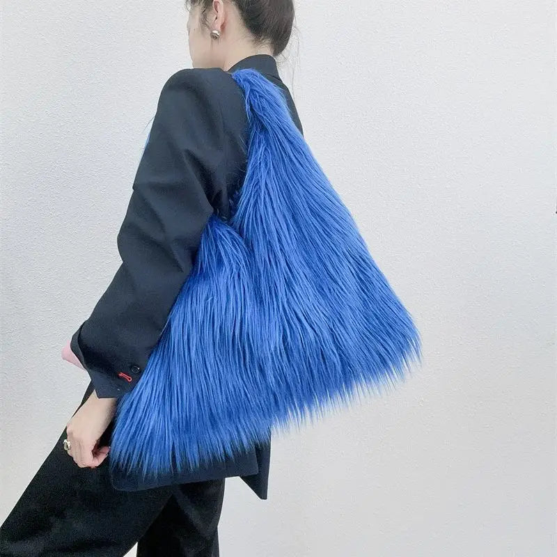 Person holding a blue fluffy bag against a plain background