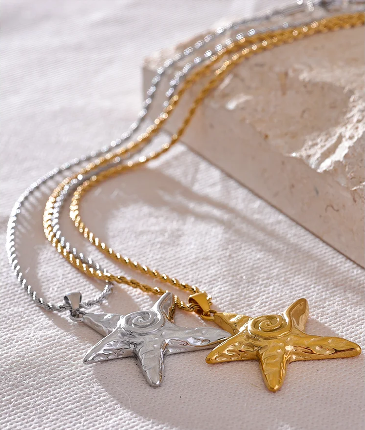 Two star-shaped pendants on a chain against a textured white background