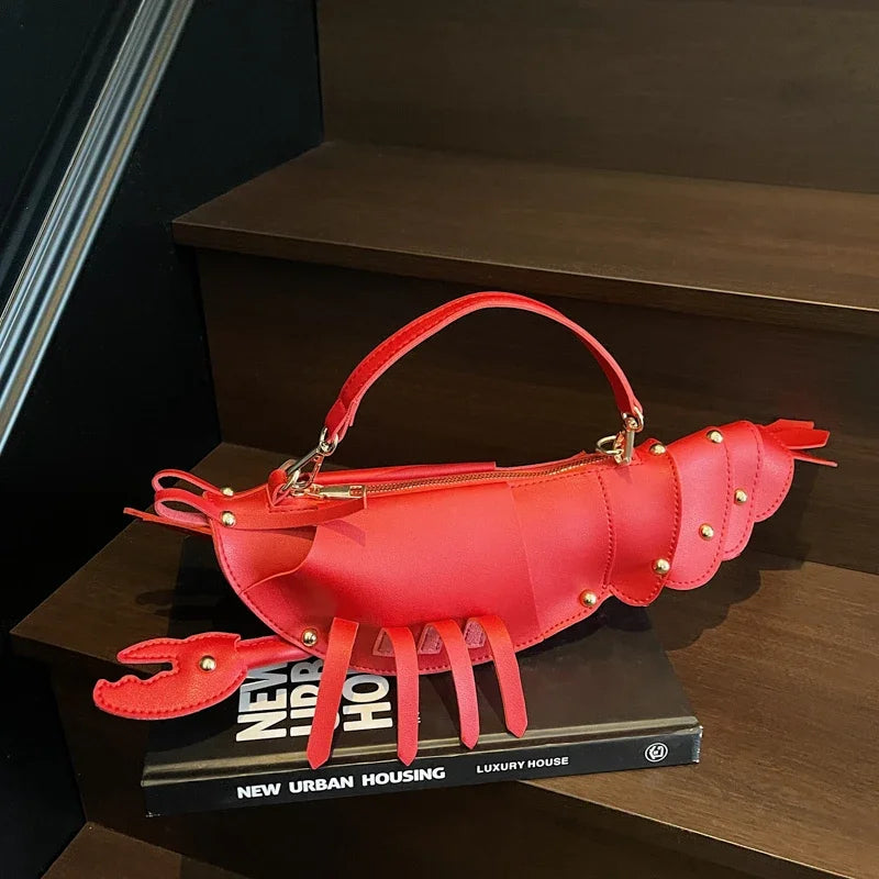 Red lobster-shaped handbag on a book with a dark background