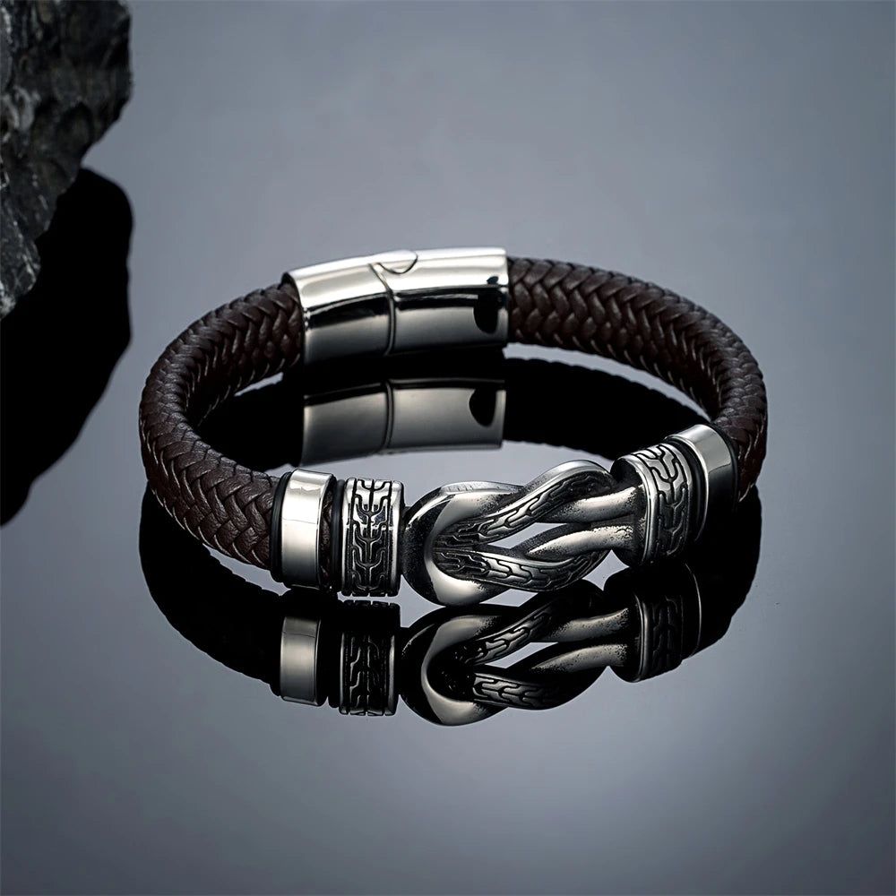 Brown braided leather bracelet with silver clasp on a reflective surface