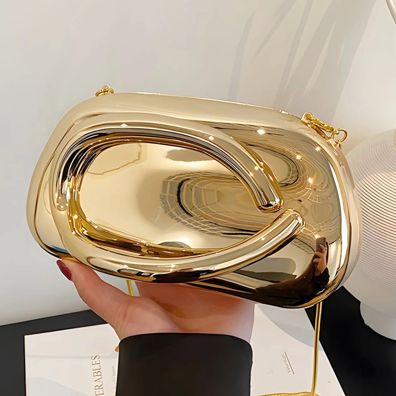 Gold handbag held by a person with a white background
