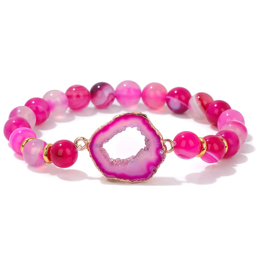 Pink beaded bracelet with a geode charm on a white background