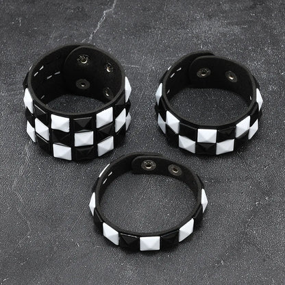 Three black and white checkered bracelets on a dark textured surface