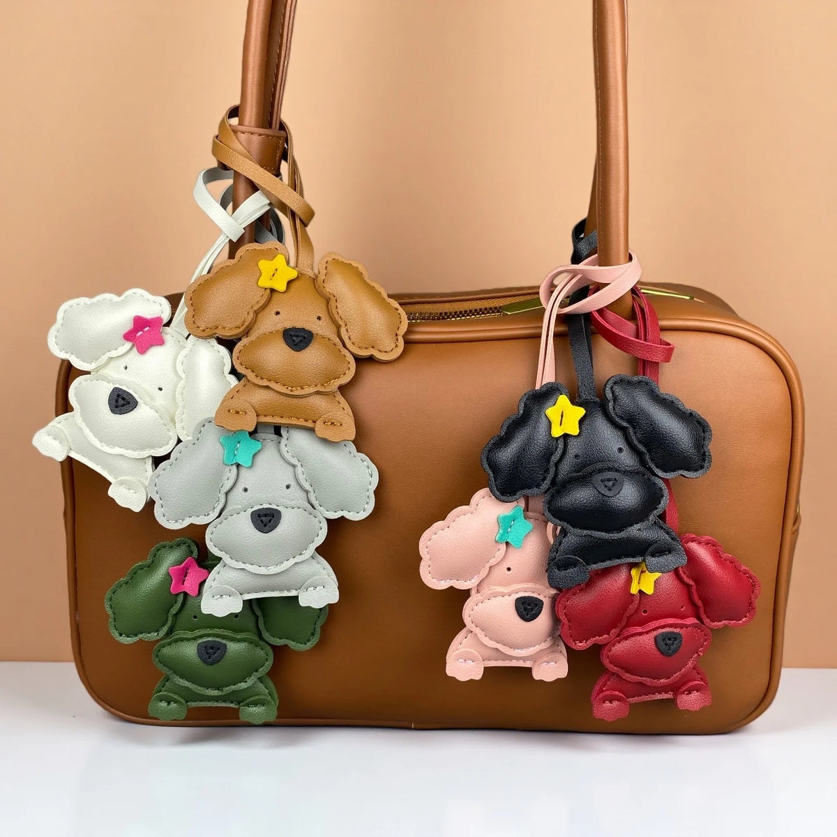 Set of colourful dog-shaped keychains on a brown handbag against a beige background