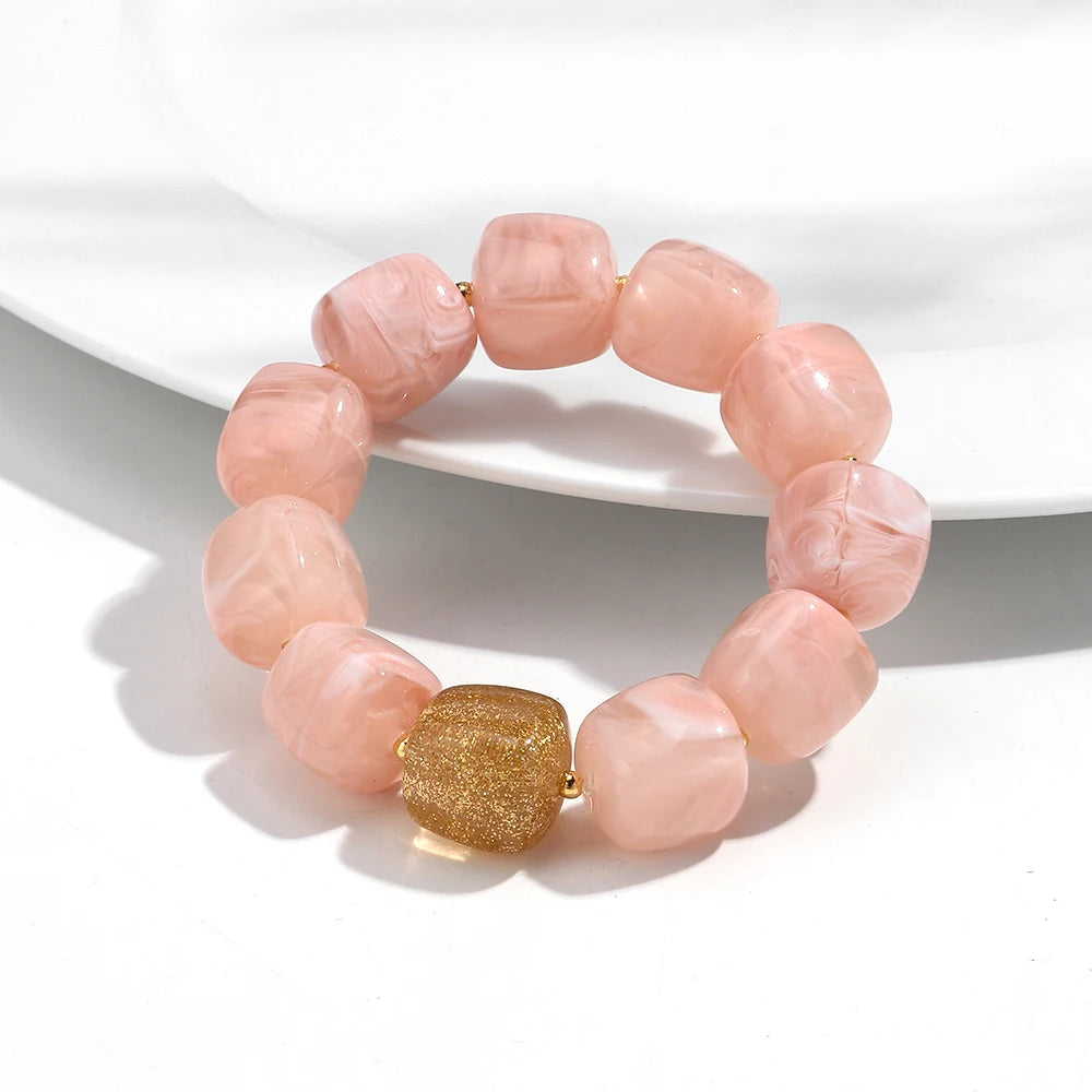 Pink beaded bracelet with a gold accent on a white background