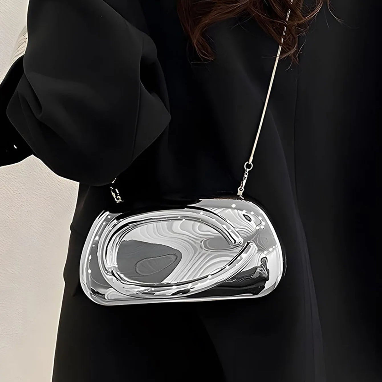 Person wearing a black coat with a silver clutch bag.
