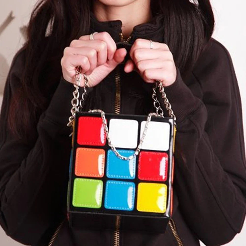 Person holding a colourful square-patterned handbag with a chain strap.