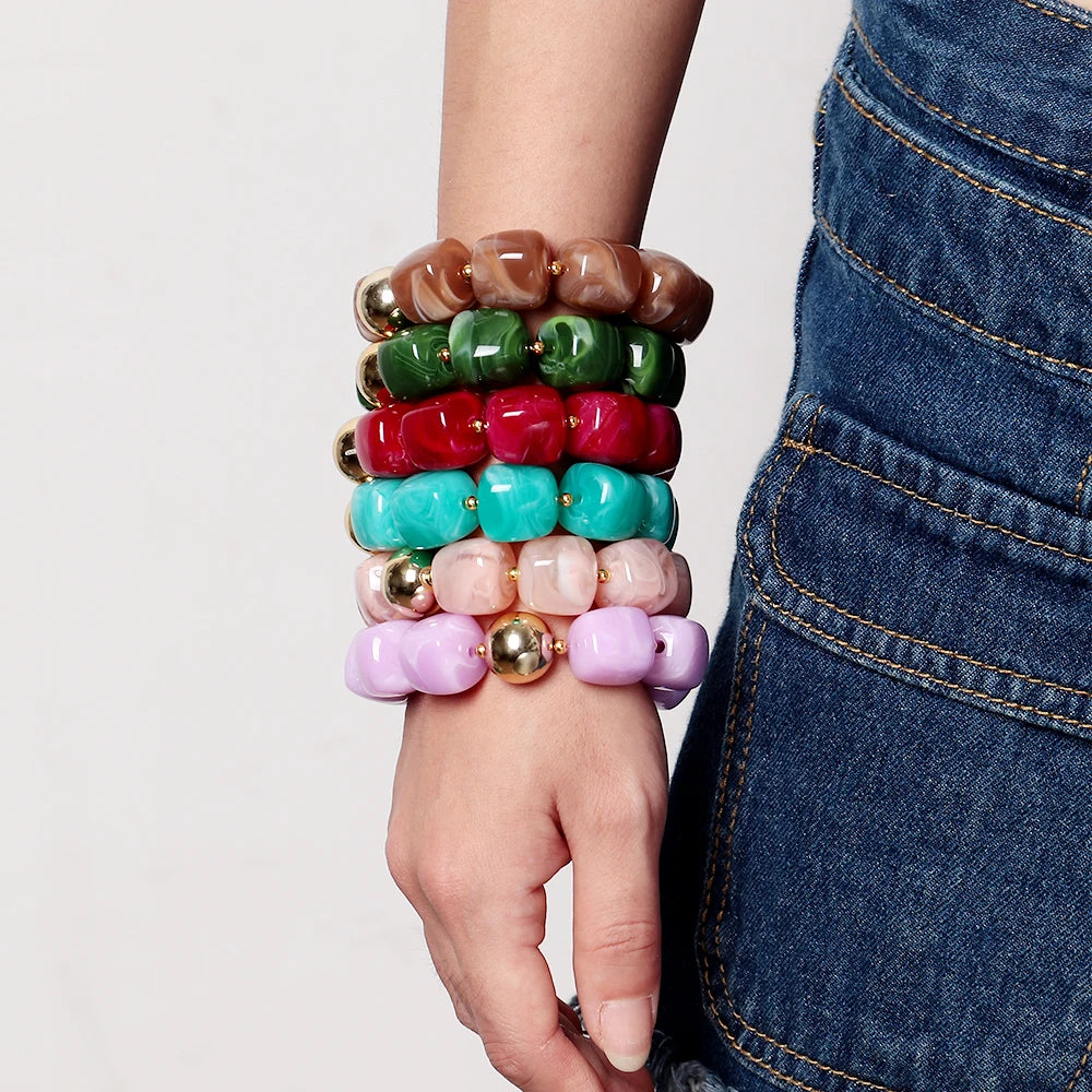 Colourful beaded bracelets on a wrist with a neutral background
