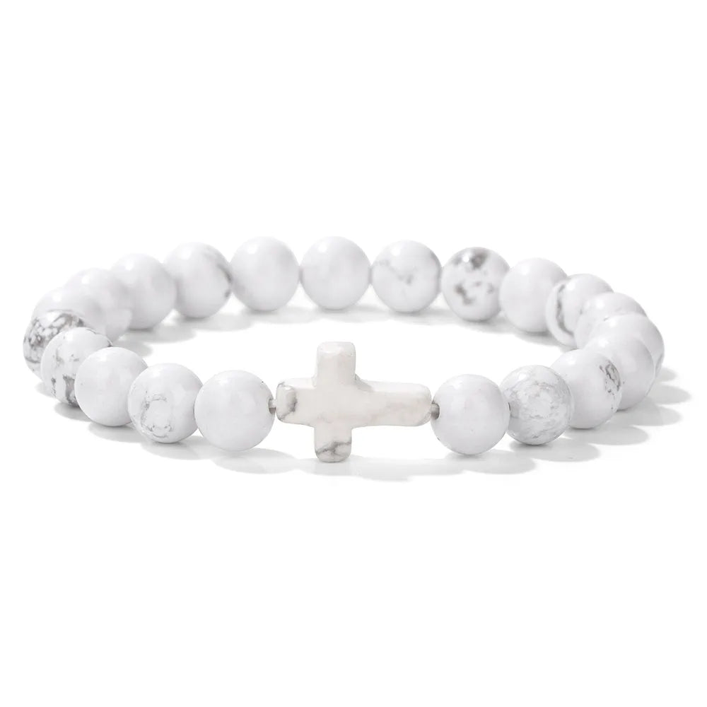 White beaded bracelet with a cross charm on a white background