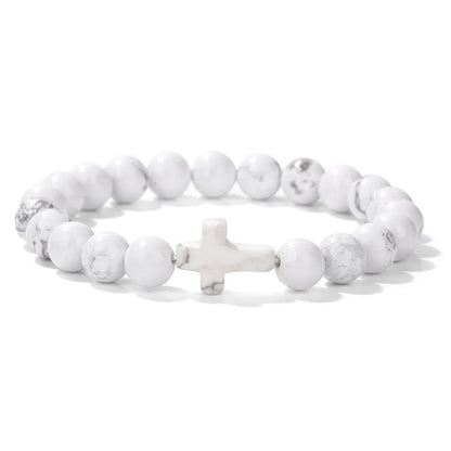 White beaded bracelet with a cross charm on a white background