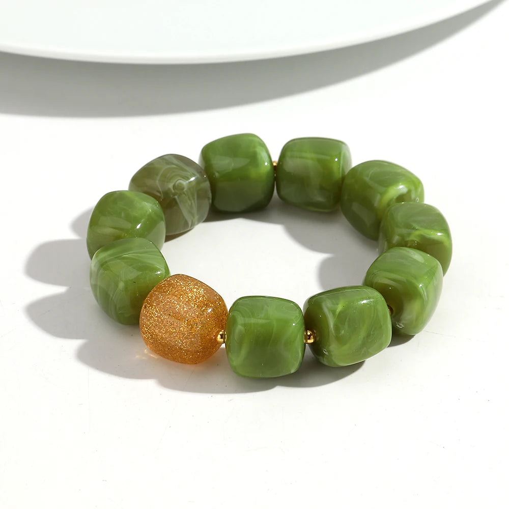 Green beaded bracelet with a gold bead on a white background