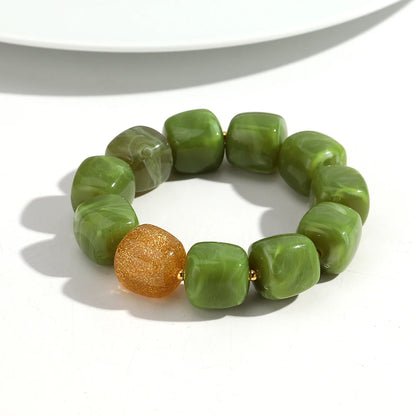 Green beaded bracelet with a gold bead on a white background