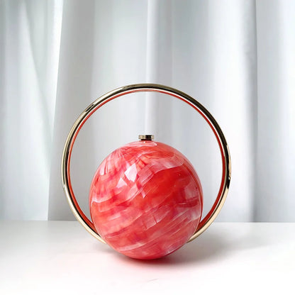 Clutch bag with a pink marbled sphere and gold circular frame on a white background