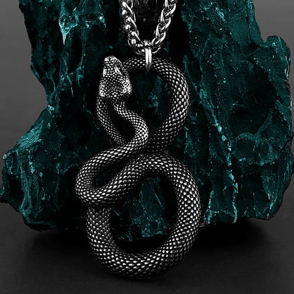 Silver snake pendant necklace on a textured green stone background