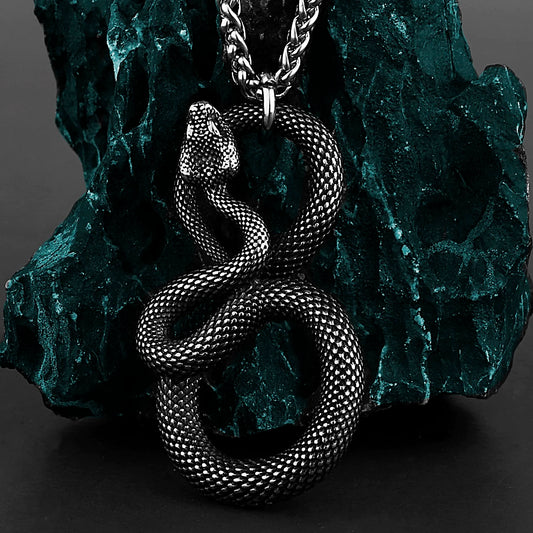 Silver snake pendant necklace on a textured green stone background