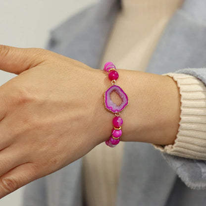 Pink beaded bracelet on a wrist with a neutral background
