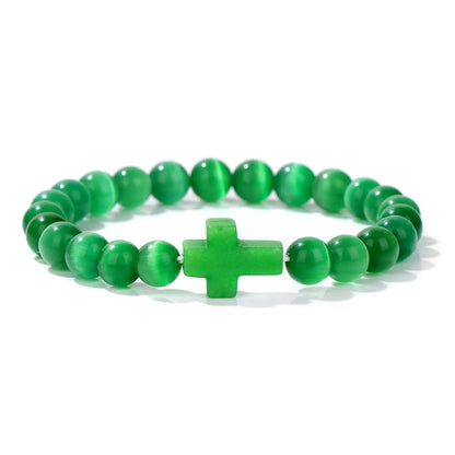 Green beaded bracelet with a cross charm on a white background