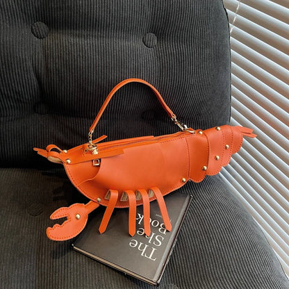 Brown lobster-shaped handbag on a dark surface with a book underneath