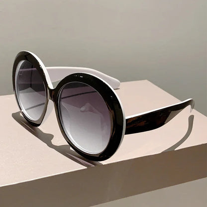 Sunglasses with black frames and gradient lenses on a beige surface