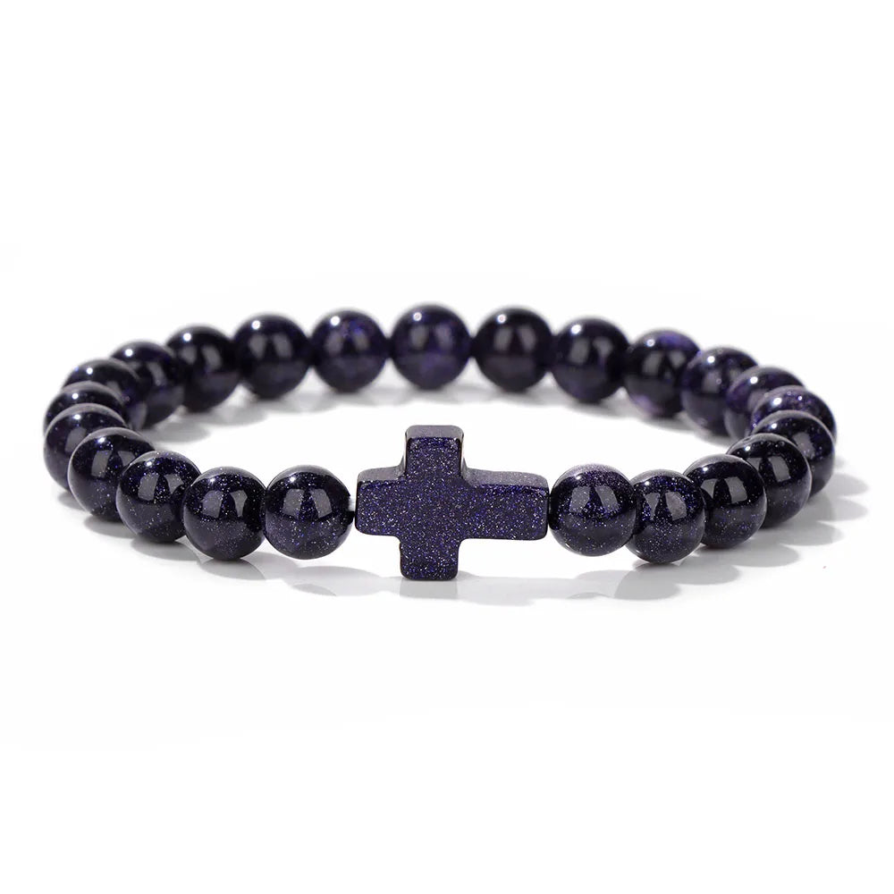 Blue beaded bracelet with a central cross charm on a white background