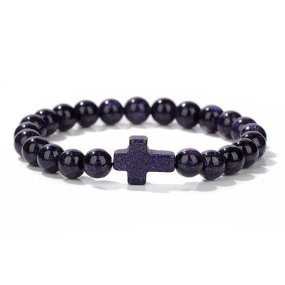 Blue beaded bracelet with a central cross charm on a white background