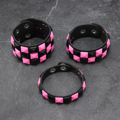 Three black and pink checkered bracelets on a grey surface