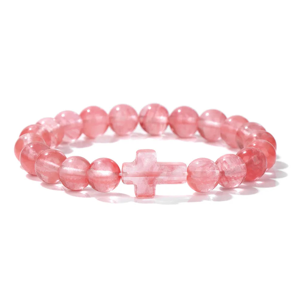 Pink beaded bracelet with a cross charm on a white background
