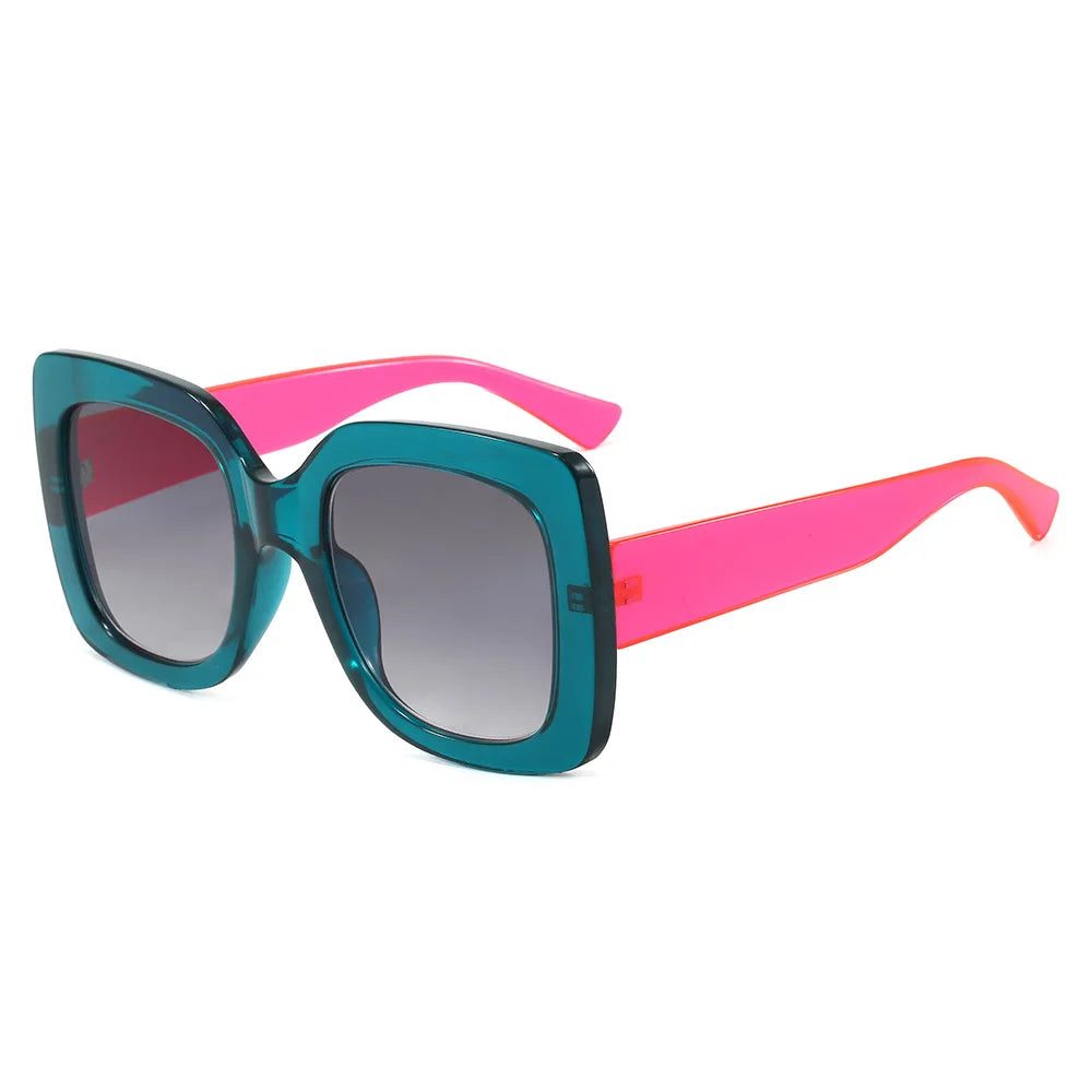 A pair of oversized square sunglasses with a translucent teal-blue frame, bright pink arms, and dark gradient lenses, shown on a plain white background.