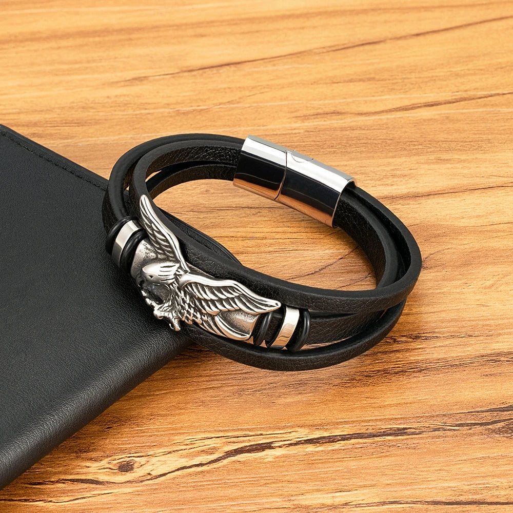 Black leather bracelet with silver eagle charm on a wooden surface