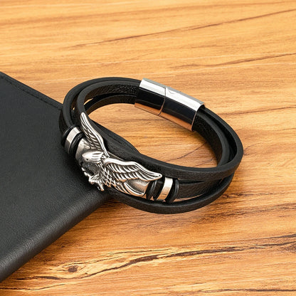 Black leather bracelet with silver eagle charm on a wooden surface