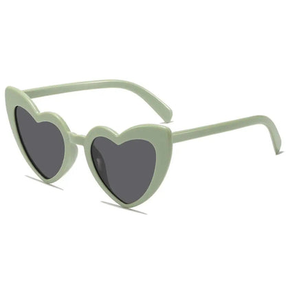 Heart-shaped sunglasses with green frame and dark lenses on a white background