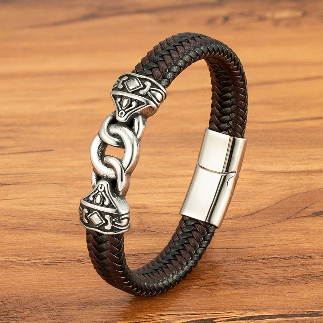 Brown braided leather bracelet with silver metal clasp on a wooden surface