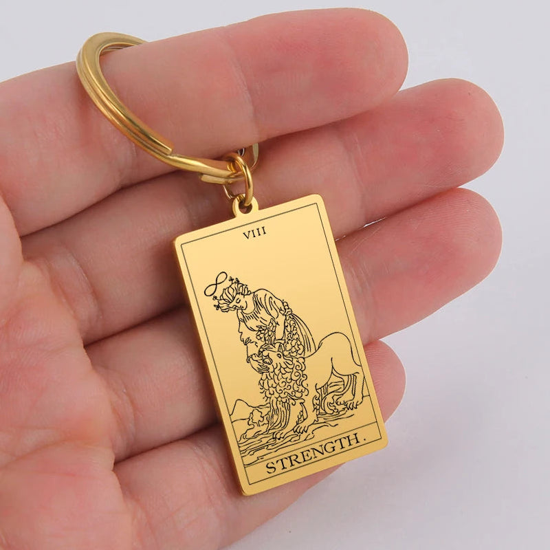 Gold tarot card keychain held in a hand against a white background