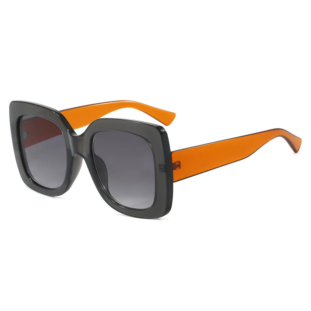 Oversized square sunglasses with a thick black frame, gradient grey lenses, and bright orange arms, shown on a plain white background.
